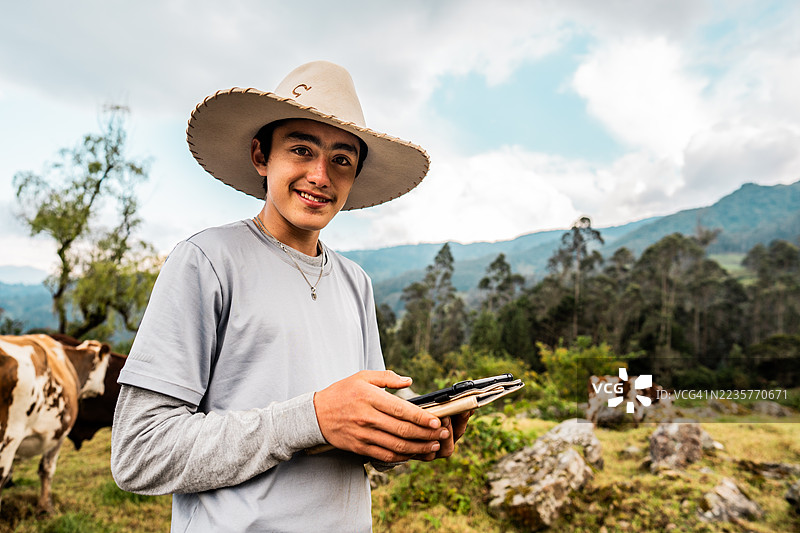 哥伦比亚昆迪纳马卡省农场里，一位青少年男孩使用数码平板电脑的肖像图片素材