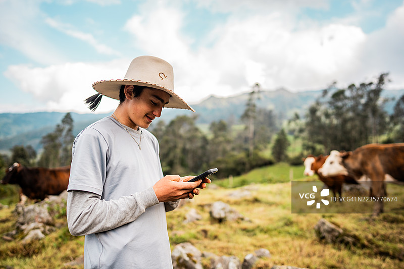 哥伦比亚昆迪纳马卡省农场里，一名青少年男孩正在使用手机图片素材