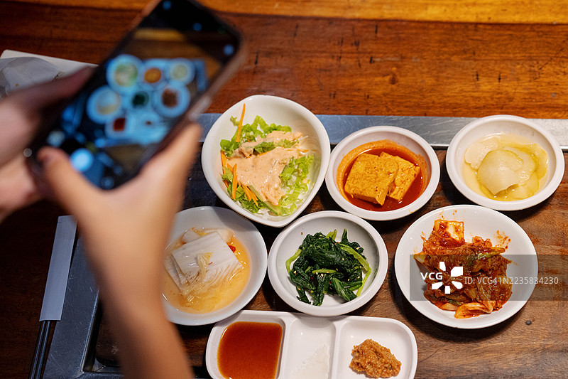 特写镜头：一个人用智能手机拍摄各种韩国小菜（Banchan）图片素材