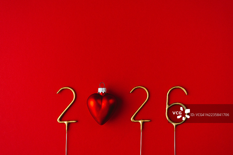 2026年由金色烟花和红色心形装饰球组成，背景为红色。图片素材