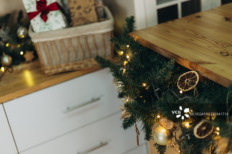 圣诞装饰品装点着厨房，常青树枝编成的花环旁边放着装饰好的礼物篮。图片素材