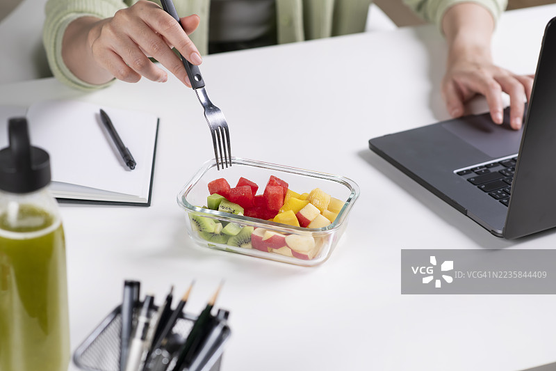 商务女性在办公室工作时吃着新鲜水果的餐前准备。图片素材