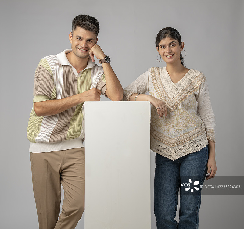 年轻情侣在白色背景前举着空白标牌图片素材
