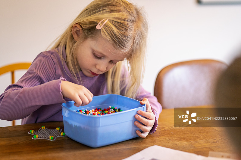 专注的金发女孩在家里解决马赛克 pegboard 星星拼图图片素材