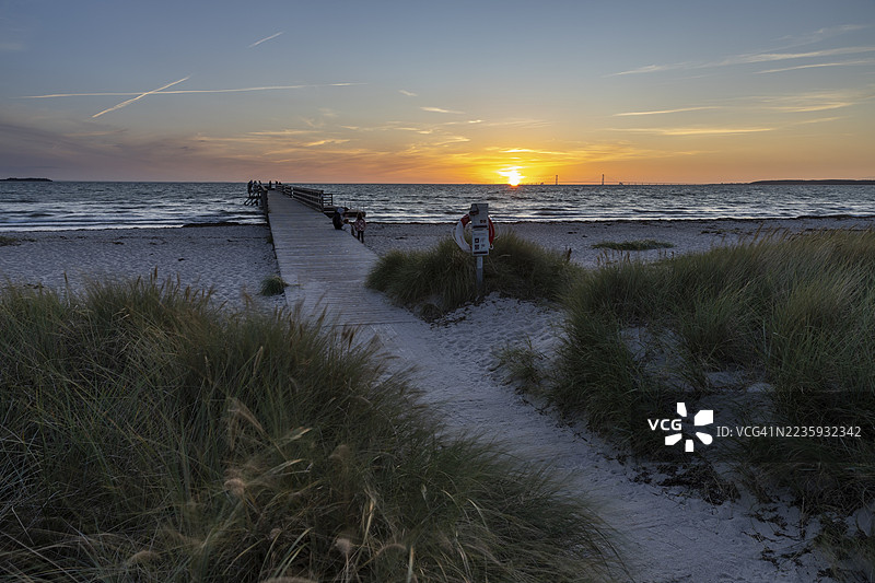 海上日落天空，木栈道和救生圈，被海滩草和宁静的水面环绕，科巴克海滩，西兰，丹麦图片素材