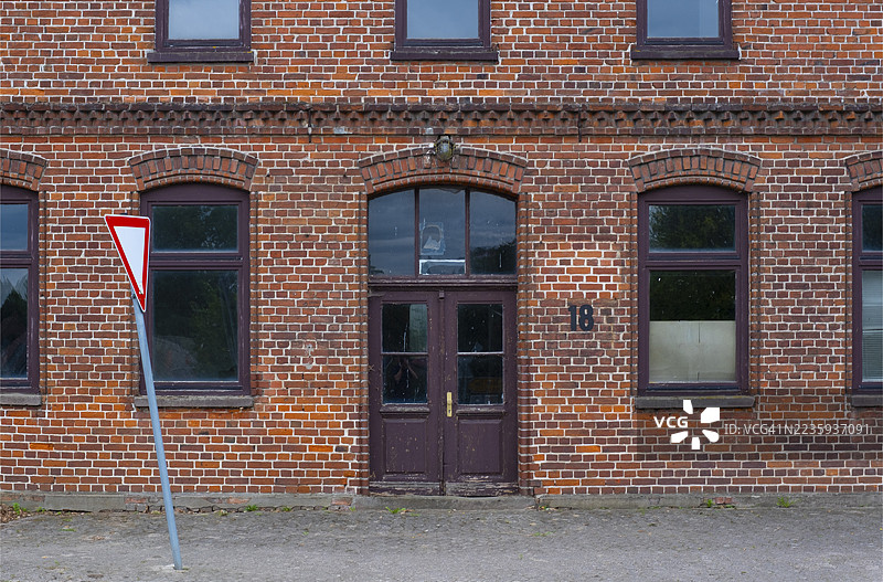 砖砌建筑入口区域的景观,前面有一个倾斜的交通标志,位于德国下萨克森州布鲁赫豪森-菲尔森的乌恩岑。图片素材