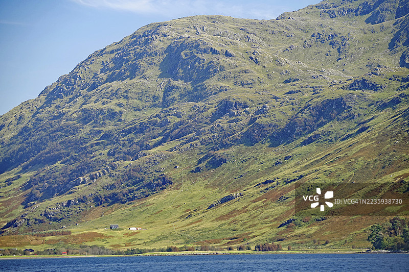 苏格兰高地诺伊达特地区，清澈天空下的大山绿坡与零星农舍。图片素材