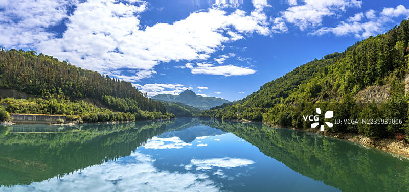 宁静的伊比尔水库映照着天空和周围的山丘，营造出巴斯克地区吉普斯夸心脏地带自然之美的宁静全景。图片素材