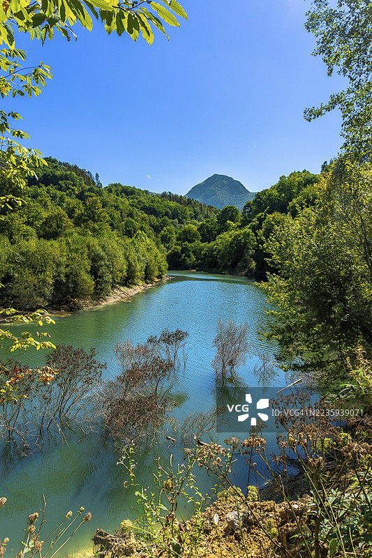 伊比乌尔水库映照着生机勃勃的树木和被郁郁葱葱植被装点的雄伟山脉，阳光明媚的夏日，位于西班牙巴斯克地区吉普斯夸的托洛萨。图片素材