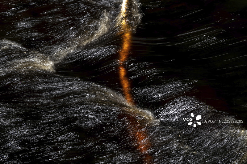 在快速流动的溪流中，一根白桦树的树枝，水面上的光线反射，挪威图片素材