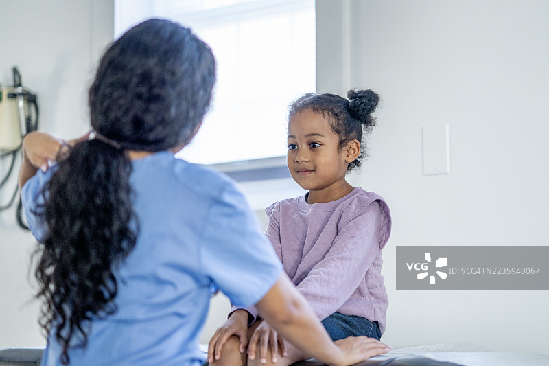 年轻儿童在阳光明媚的诊所接受女护士的检查图片素材
