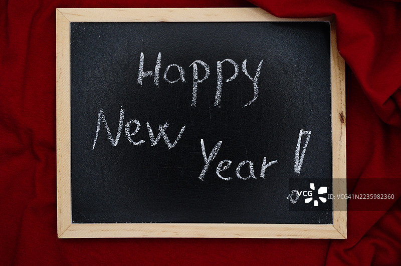 黑板上用粉笔写的“新年快乐”祝福，背景为红色图片素材
