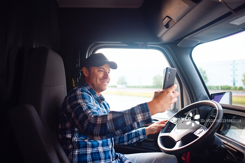 卡车司机在车厢内微笑着使用智能手机图片素材