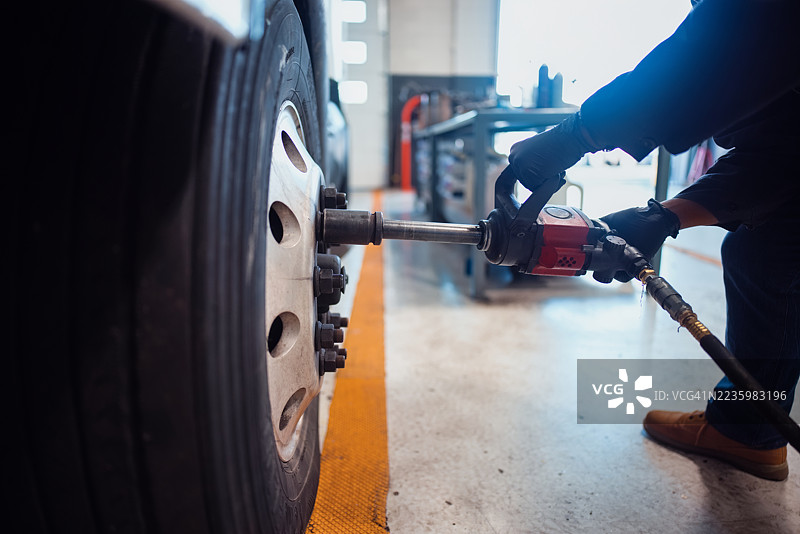 机械师在车间使用电动工具紧固车辆轮胎螺栓图片素材
