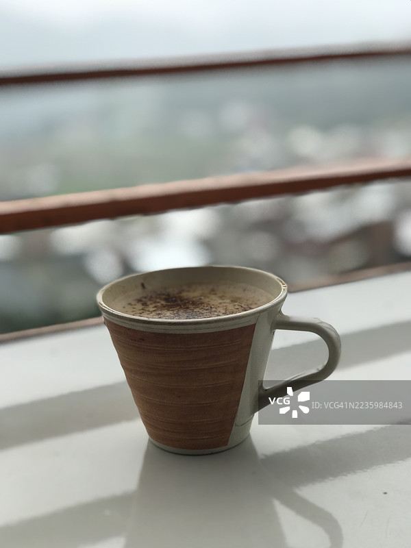 阳台上咖啡杯的特写，背景是户外景色图片素材