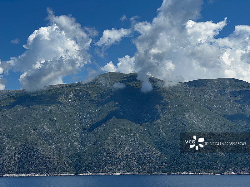 阿尔巴尼亚一座山的戏剧性风景，云雾笼罩着山顶，俯瞰着清澈蓝色的海洋和晴朗的天空。图片素材