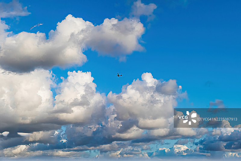 从低角度拍摄，一架小型飞机在蓝天中穿行，天空布满了白色和灰色的云朵，地点位于英国克罗伊登。图片素材