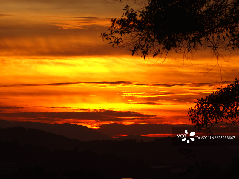 马来西亚库林的山脉剪影下，戏剧性的日落天空，橙色和黄色的云彩生动夺目。图片素材