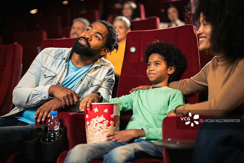 一家人在电影院观看电影，吃着爆米花，享受快乐时光图片素材