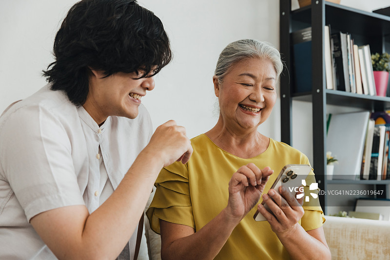 家人窝在舒适的客厅里，一起看手机，享受温馨的亲子时光图片素材