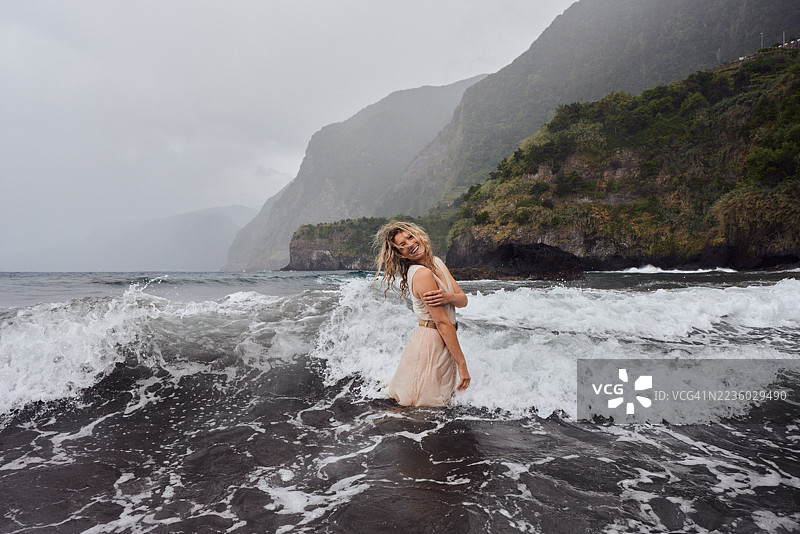 无忧无虑的女人在海边的雨天中尽情玩乐。图片素材