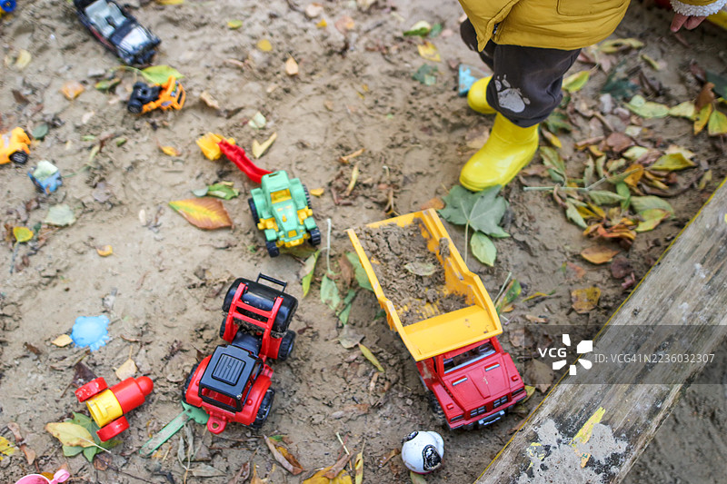 俯视穿着黄色夹克的男孩在冬季沙箱中玩耍图片素材