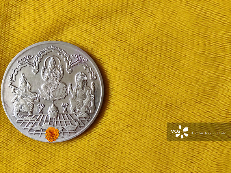 女神拉克希米/萨拉斯瓦蒂/甘尼什神银币放在黄色丝绸布上/纳瓦拉特里节/排灯节/丹特拉斯节/节日/留白空间图片素材