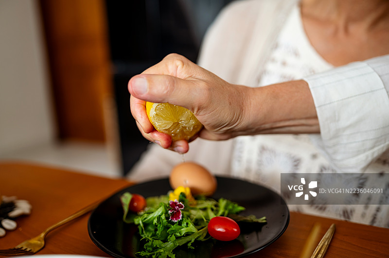 在餐桌上用手挤柠檬汁到新鲜沙拉上图片素材