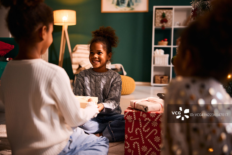 微笑的黑人孩子从姐姐那里收到圣诞礼物图片素材