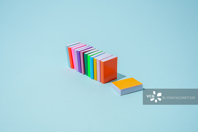 色彩斑斓的书籍在浅蓝色背景上竖立和躺着图片素材
