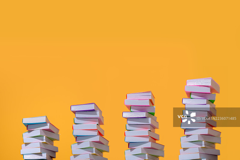 在橙色背景上堆叠的五彩斑斓的书籍，象征着成长图片素材