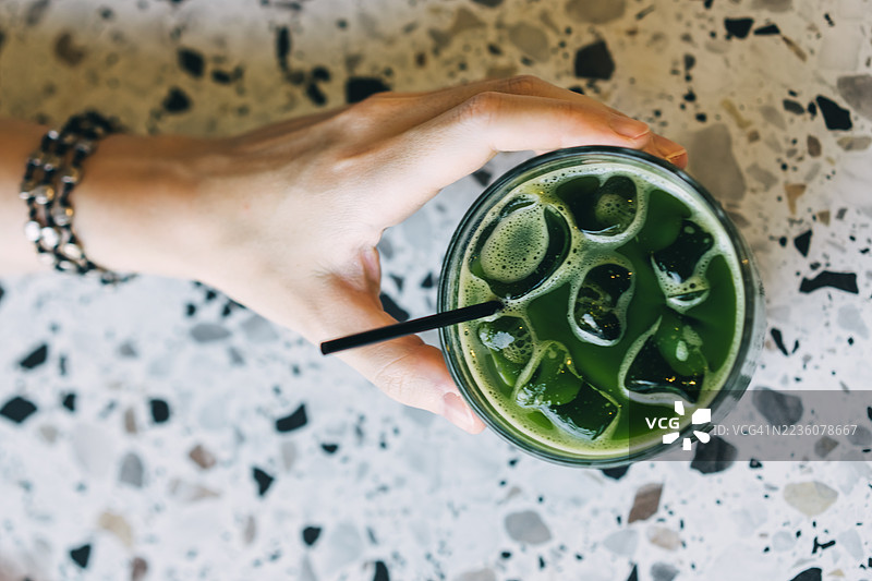 透明玻璃杯中的冰镇抹茶。绿茶配冰块和吸管。图片素材