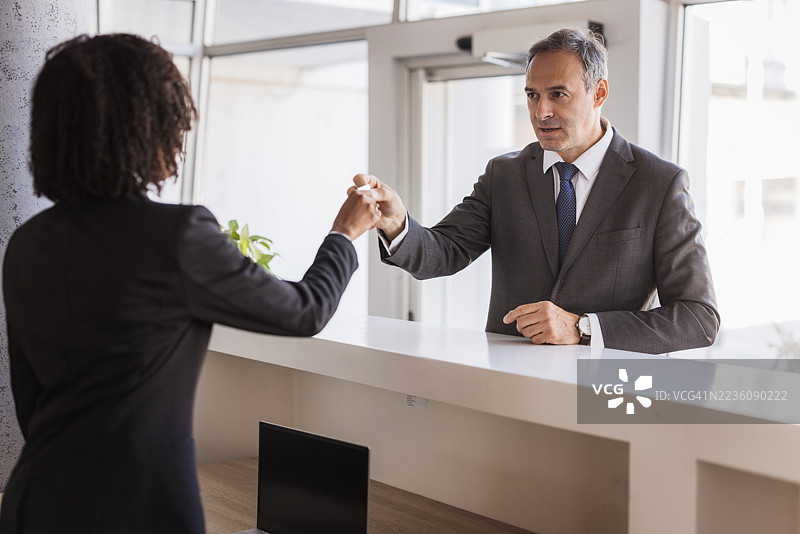 商务人士在接待处将文件递给接待员图片素材