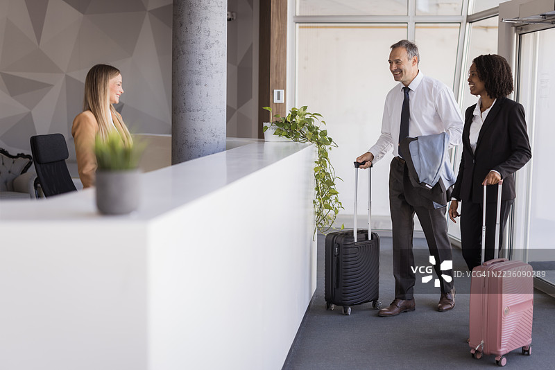 商务人士推着行李箱抵达酒店接待处图片素材