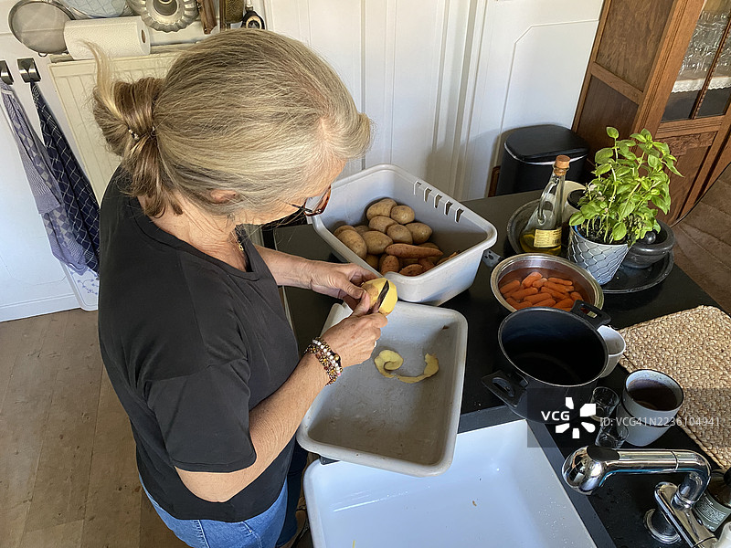 一位年长女性在厨房准备晚餐。图片素材