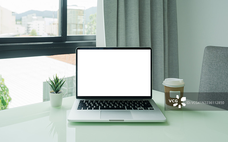 咖啡馆背景下桌子上的笔记本电脑空白屏幕。咖啡店桌子上的笔记本电脑空白屏幕，背景模糊。图片素材