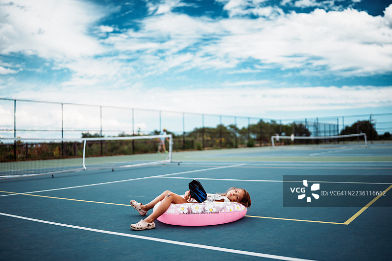 年轻女孩在皮克球场上放松，坐在泳池浮筒上图片素材
