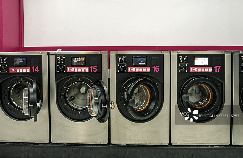 洗衣房内部，排成一排的洗衣机。图片素材