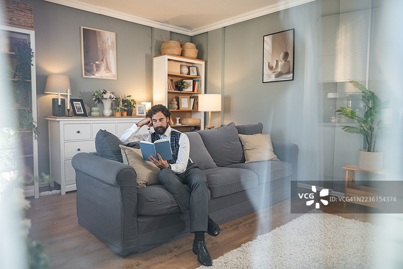 男人在沙发上放松地阅读书籍图片素材