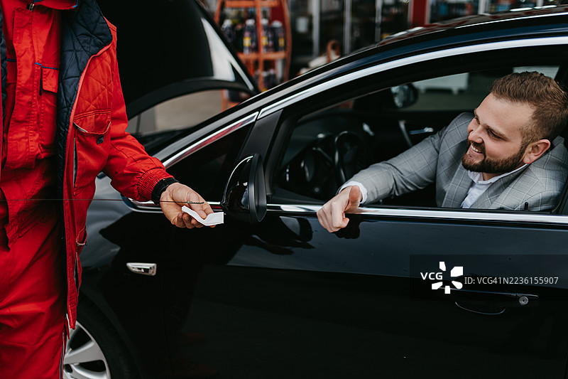 机械师为微笑的顾客检查汽车油液图片素材