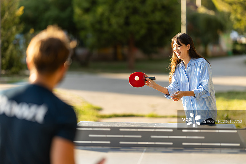 年轻朋友们在阳光明媚的日子里轻松地打乒乓球图片素材