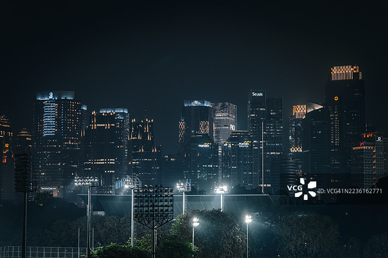 高角度俯瞰夜晚的现代城市，灯火辉煌的建筑和体育场在夜空中闪耀，印度尼西亚，雅加达，塞纳扬图片素材
