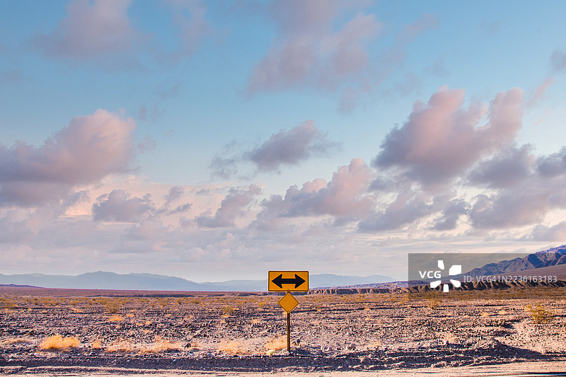 意大利广袤沙漠景观下的方向箭头标志与戏剧性的日落天空图片素材