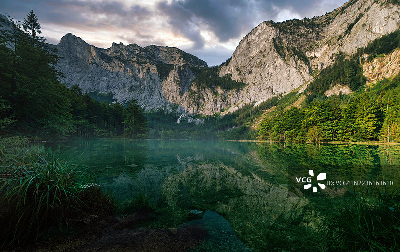 奥地利朗巴特湖，宁静的山间湖泊，水面如镜，倒映着葱郁的绿植和戏剧性的天空图片素材