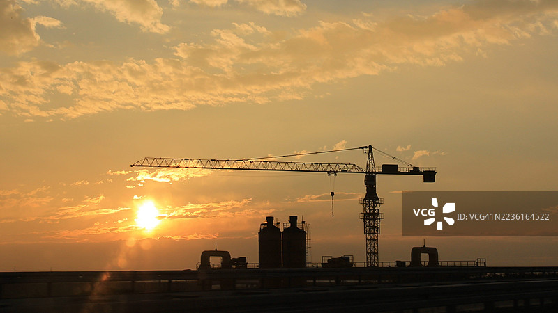 德国一座建筑起重机的剪影映衬在戏剧性的日落天空中图片素材