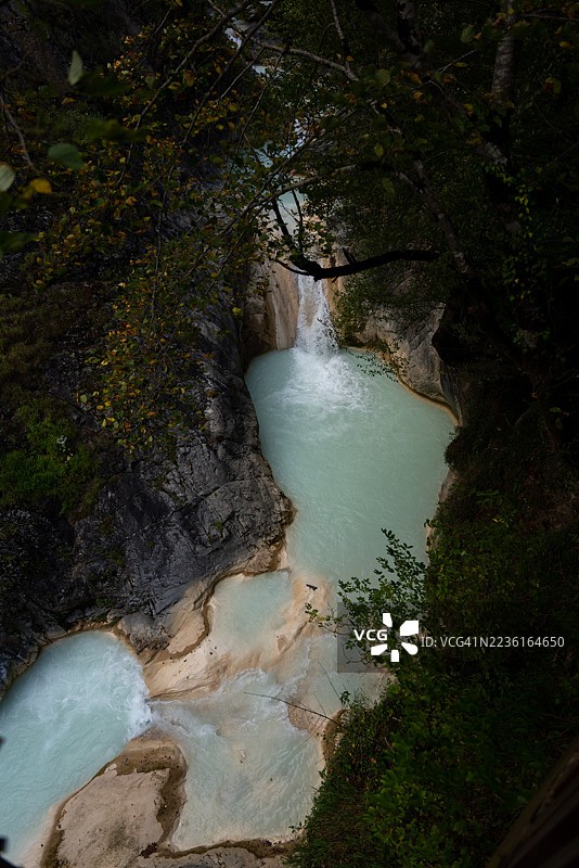 高角度俯瞰瀑布倾泻入碧绿色水池的郁郁葱葱的森林图片素材