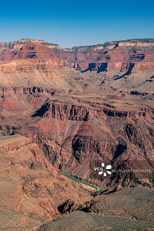 令人惊叹的空中视角展示了大峡谷的戏剧性分层岩石和科罗拉多河在广阔的景观中流淌,蓝天清澈,位于美国弗拉格斯塔夫,大峡谷国家公园基金会。图片素材