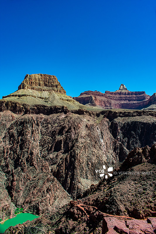 壮观的岩石山脉在晴朗的蓝天下，下面是一条生机勃勃的绿色河流，弗拉格斯塔夫，美国，国家公园大峡谷基金会图片素材