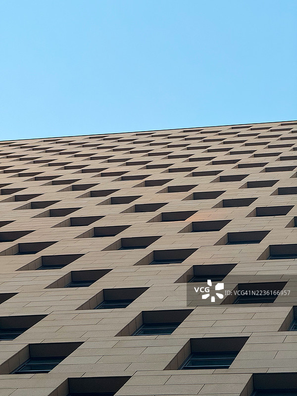现代建筑外立面的低角度视图，重复的方形窗户与晴朗的蓝天形成图案，中国，杭州图片素材