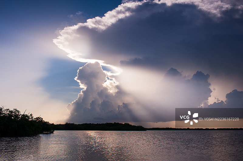宁静湖面上的戏剧性日落，树木剪影与发光的云彩，位于美国佛罗里达湾图片素材